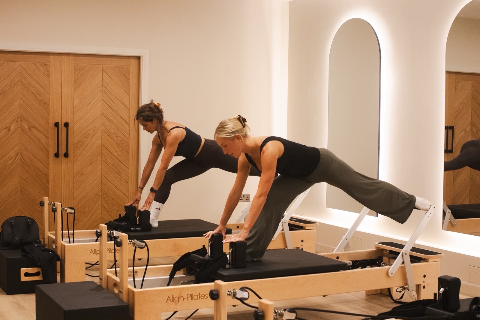 Two clients stretching on reformers in the FORME studio